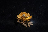 Gold flower-shaped brooch with gemstones on a black background