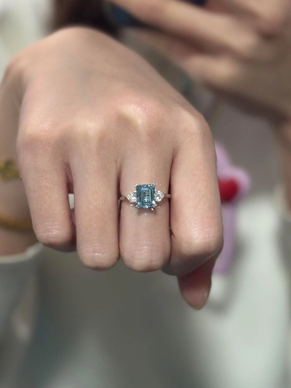 Close-up of a hand wearing a ring with a blue gemstone.