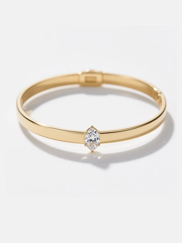 Gold bracelet with a diamond on a light gray background