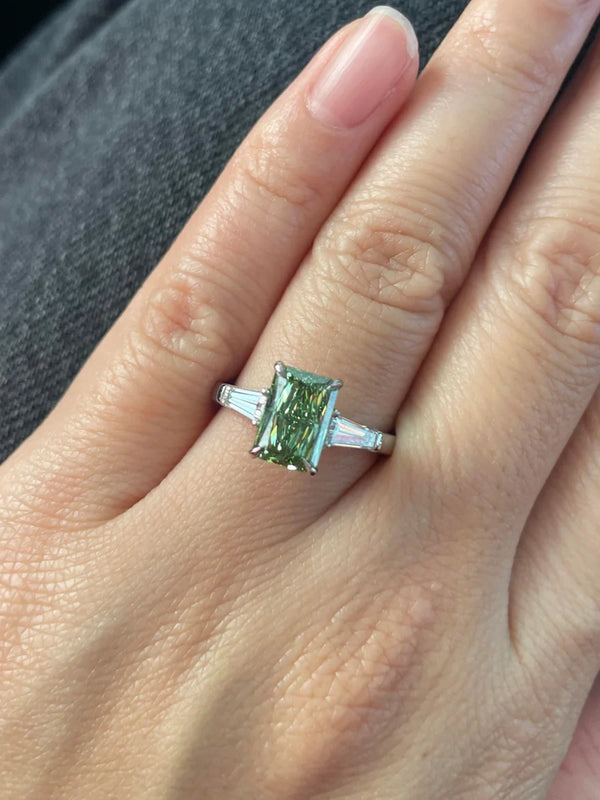 Green gemstone ring on a hand with a neutral background