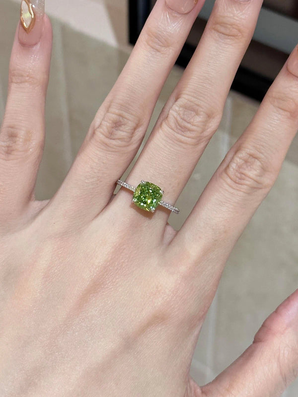 Hand wearing a ring with a green gemstone on a neutral background
