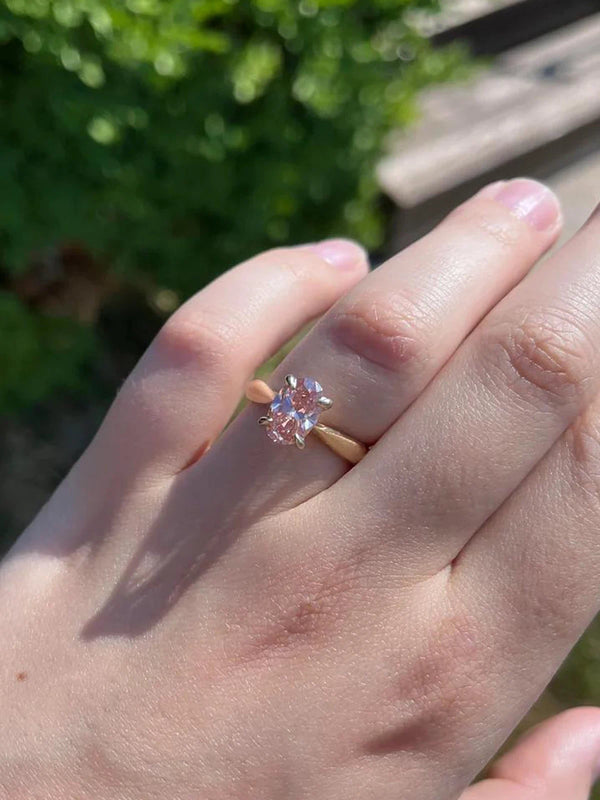 Hand wearing a ring with a diamond, outdoors