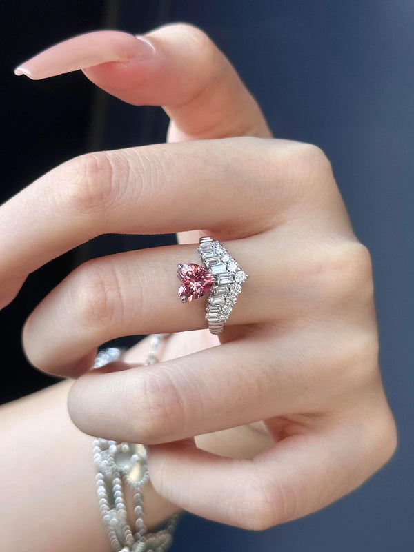 Hand wearing a pink gemstone ring with a diamond band on a dark background